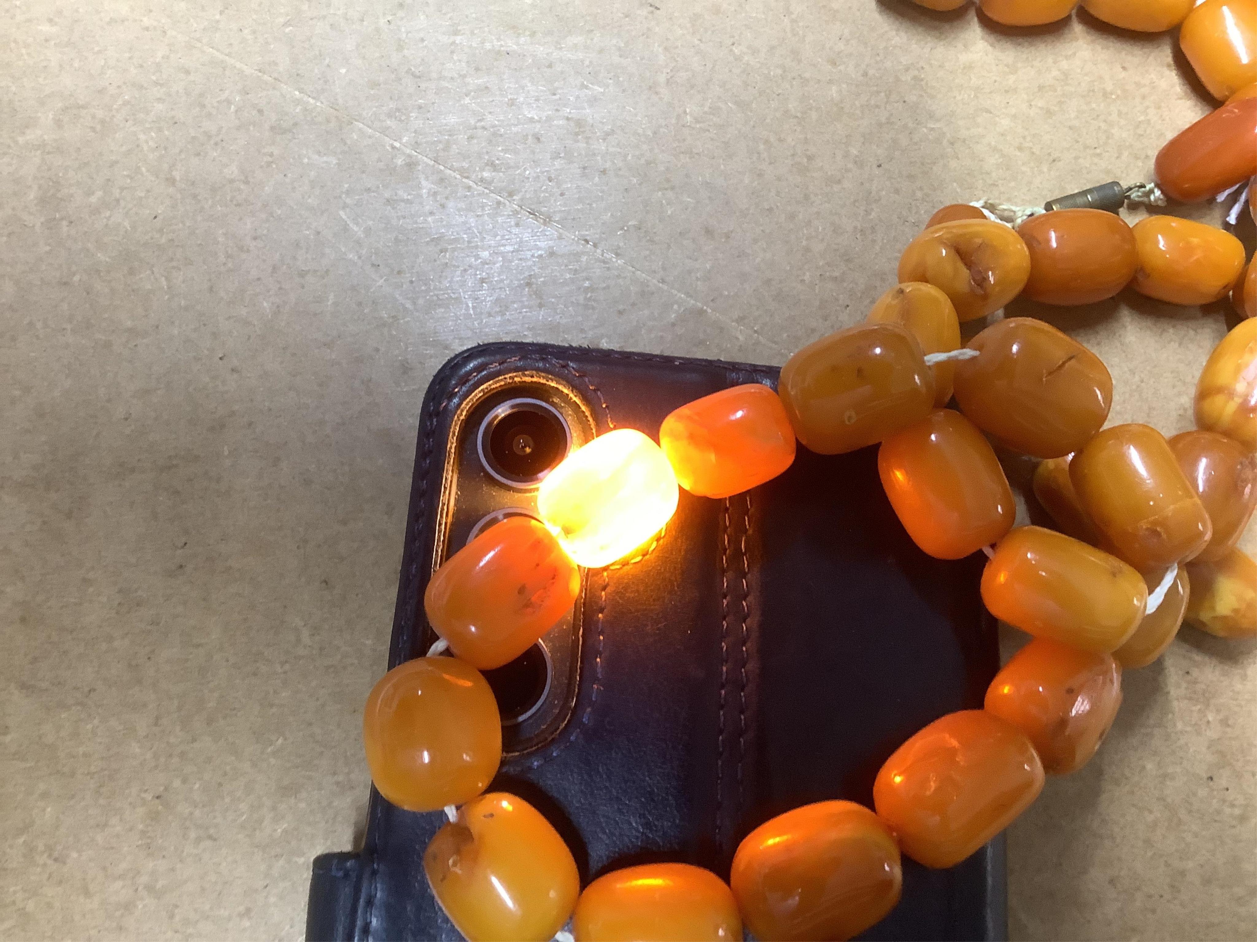 A single strand oval and barrel shaped amber bead necklace, 90cm, gross weight 102 grams. Condition - poor to fair